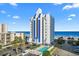 Coastal condo building features a swimming pool, parking, and overlooks an expansive beach with beautiful blue skies at 2609 South Ocean Blvd. # 702, North Myrtle Beach, SC 29582