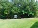 Backyard with a lush lawn, mature trees, and a decorative sign at 266 Tall Palms Way, Little River, SC 29566