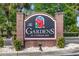 Welcoming brick sign for The Gardens at Cypress Bay, featuring tropical flowers and lush landscaping at 4142 Hibiscus Dr. # 20-202, Little River, SC 29566