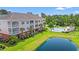 Exterior view of a building with a pool, pond, landscaping, and mature trees at 4142 Hibiscus Dr. # 20-202, Little River, SC 29566