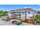 Three-story condo building featuring white balconies, red brick accents, and palm tree landscaping on a sunny day at 4142 Hibiscus Dr. # 20-202, Little River, SC 29566