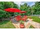 Beautiful outdoor patio features a dining table with red umbrellas, a grill, and lush green landscaping at 504 Sea Vista Ln., North Myrtle Beach, SC 29582