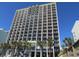 Multi-story condo building featuring private balconies, palm trees, and vibrant colors against a clear blue sky at 6804 N Ocean Blvd. # 1023, Myrtle Beach, SC 29572