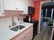 Modern kitchen with white cabinets, a black stove, and stainless-steel sink; view into the bedroom at 6804 N Ocean Blvd. # 1023, Myrtle Beach, SC 29572