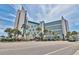Striking beachfront condo building with palm trees and colorful landscaping along a scenic road at 7100 North Ocean Blvd. # 617, Myrtle Beach, SC 29577