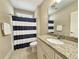 Bathroom featuring granite counters, cabinetry, a combination tub and shower with a blue striped shower curtain at 82 Mingo Dr. # 2D, Pawleys Island, SC 29585