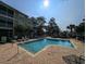 Outdoor swimming pool with lounge chairs on a sunny day surrounded by trees and the condo buildings at 82 Mingo Dr. # 2D, Pawleys Island, SC 29585