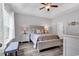 Bright bedroom features a ceiling fan, tray ceiling, wood-look floors, and a bench by a sunny window at 832 Windsor Rose Dr., Conway, SC 29526