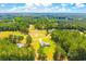 An expansive aerial view showing the home set amongst a landscape of lush trees and vibrant fields at 1013 Happy Ln., Galivants Ferry, SC 29544