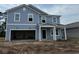 Two-story blue home with a front porch, unfinished landscaping, and a two-car garage at 1039 Laconic Dr., Myrtle Beach, SC 29588