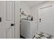 A modern laundry room features a washer and dryer, a shelf, black and white tile flooring, and a door at 1205 Cymmer Ct., Conway, SC 29527