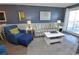 Living room features a striped sofa, blue club chair, and access to balcony at 1310 N Waccamaw Dr. # 102, Garden City Beach, SC 29576