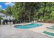 Community pool with blue water, brick patio, lounge chairs, trees and black metal fence at 157 Egret Run Ln. # 523, Pawleys Island, SC 29585