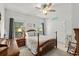 Bedroom showcasing a wooden bed frame, ceiling fan, and natural light through large windows at 1833 Lake Egret Dr., North Myrtle Beach, SC 29582