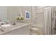 Clean bathroom with a shower-tub combination, floral artwork, and fresh white towels for a spa-like experience at 234 Ladyfish Loop, Sunset Beach, NC 28468