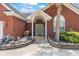 Close-up of a red brick home's inviting entryway, showcasing a neatly landscaped garden and charming front door at 2384 Covington Dr., Myrtle Beach, SC 29579