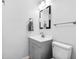 Bathroom with gray cabinets, white sink, toilet, large mirror, and lighting at 315 73Rd Ave. N # 2, Myrtle Beach, SC 29572