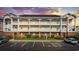 A beautiful three-story condo building with brick base, charming balconies, and accessible parking, set against a colorful sunset at 3983 Forsythia Ct. # 301, Myrtle Beach, SC 29588