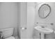 Clean and modern half-bath featuring a pedestal sink, decorative mirror, and a toilet at 4232 Pointer Ct., Myrtle Beach, SC 29579