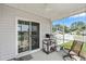 Cozy screened porch with sliding glass door, ceiling fan, grill, and comfortable chair at 568 Mossbank Loop, Longs, SC 29568