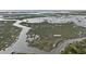 This aerial shot of a marsh features winding waterways and vibrant marsh grasses under a bright sky at 58 Fathom Ln., Murrells Inlet, SC 29576