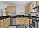 Kitchen with stainless steel appliances, sleek black countertops, light wood cabinets, and tile flooring at 1125 Camellia Dr., Surfside Beach, SC 29575