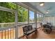This enclosed porch has black wrought iron furniture, wood floors, and ceiling fans at 141 Cayman Loop, Pawleys Island, SC 29585