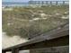 A scenic view of a sandy beach with a pier in the distance, viewed from the top of wooden stairs at 1432 Seahouse Ct., Surfside Beach, SC 29575
