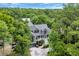 Aerial view of a two-story home nestled amongst lush trees with a private driveway and manicured lawn at 24 Jerry Ct., Pawleys Island, SC 29585