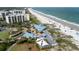 Beautiful aerial view of an oceanfront resort, buildings, beach with umbrellas, dining terrace and palm trees at 341 South Dunes Dr. # C-34, Pawleys Island, SC 29585