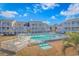 A beautiful outdoor pool at a condo complex is surrounded by lounge chairs and palm trees under a blue sky at 3700 Golf Colony Lane # 20-L, Little River, SC 29566