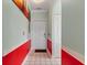 Hallway with neutral tile flooring, red accent walls, and a white front door at 4673 Wild Iris Dr. # 21-201, Myrtle Beach, SC 29577