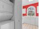 Stackable washer/dryer adjacent to bright white kitchen with red wall at 4673 Wild Iris Dr. # 21-201, Myrtle Beach, SC 29577