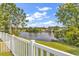 Serene backyard view featuring a picturesque pond surrounded by lush greenery and a white picket fence at 5031 Medieval Dr., Conway, SC 29526
