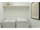 Convenient laundry room equipped with a washer, dryer, and a wooden shelf for storage at 6362 Swainson Street Sw, Ocean Isle Beach, NC 28469
