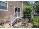 Back porch with a metal table and chairs, with stairs up to the house, plus a large bush at 6702 Jefferson Pl. # C6, Myrtle Beach, SC 29572