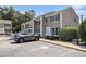 Tan townhouse with black shutters and a parking area in front of the building surrounded by mature trees and blue skies at 6702 Jefferson Pl. # C6, Myrtle Beach, SC 29572