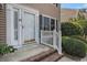 Closeup of a white front door with a brick step and small white rails surrounded by green bushes on a sunny day at 6702 Jefferson Pl. # C6, Myrtle Beach, SC 29572