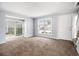 Spacious living room with neutral carpet, two large windows and a white front door leading to the front porch at 6702 Jefferson Pl. # C6, Myrtle Beach, SC 29572