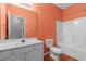 Bright bathroom with an orange accent wall, white vanity, toilet, and tub/shower combo at 100 Lazy Willow Ln. # 103, Myrtle Beach, SC 29588