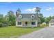 Charming two-story home with yellow siding and a lovely white porch surrounded by a well-manicured lawn at 124 Wicklow Way, Pawleys Island, SC 29585