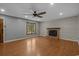 Cozy living room with hardwood floors, wood-trimmed window, a ceiling fan, and a charming brick fireplace at 124 Wicklow Way, Pawleys Island, SC 29585
