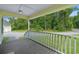 Inviting covered porch with wood floors and white railings overlooking a verdant lawn and surrounding trees at 124 Wicklow Way, Pawleys Island, SC 29585