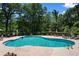 Community pool surrounded by lush trees, lounge chairs, and shade umbrellas perfect for relaxation at 125 Foxford Dr., Conway, SC 29526