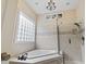 Bathroom featuring a tub, glass shower, neutral tile, chandelier and glass block window at 1501 Harbor Dr., North Myrtle Beach, SC 29582
