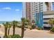 View of a beachfront high-rise building with palm trees, and partial views of the ocean and parking at 1501 S Ocean Blvd. # 351, Myrtle Beach, SC 29577