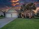 Twilight view of charming one-story home with a two-car garage, manicured lawn, and palm trees at 1635 Southwood Dr., Surfside Beach, SC 29575