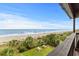 Panoramic beach view from a private balcony, showcasing the coastline, lush foliage, and inviting picnic areas at 201 76Th Ave. N # D-3, Myrtle Beach, SC 29572
