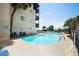 Community pool with lounging chairs, palm trees, and building at 201 76Th Ave. N # D-3, Myrtle Beach, SC 29572