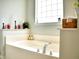 A bright bathroom featuring a tub with decorative candles and plants near the window at 230 Vermillion Dr., Little River, SC 29566
